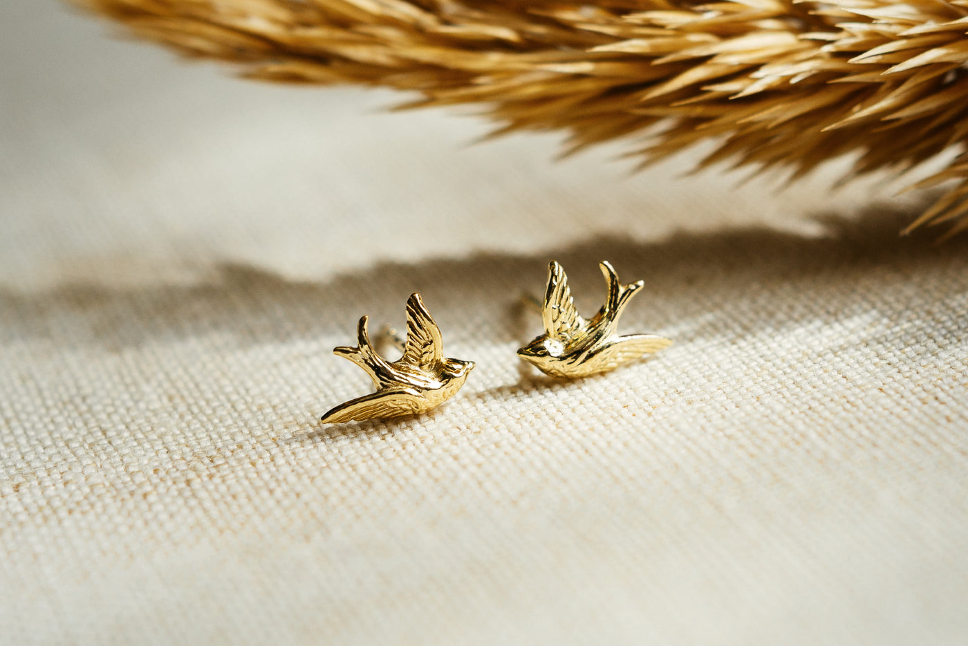 Kleine süße Vogelohrringe. Goldene Schwalben